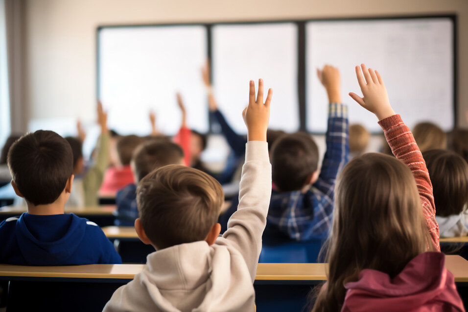 children at lesson in classroom, first bell, children in school uniforms sitting by desks. Knowledge day concept. Defocussed background